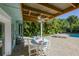 Covered outdoor patio with a dining table, fan, and lush tropical landscaping in the background at 507 Spring Ave, Anna Maria, FL 34216