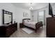 Cozy bedroom with a dark wood bed frame, dresser and bedside table, under a chandelier at 5651 Trevesta Pl, Palmetto, FL 34221