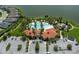 Aerial view of a community pool and clubhouse with a red-tiled roof, with palm trees, landscaping, playground, and lake view at 5651 Trevesta Pl, Palmetto, FL 34221