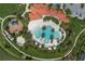 Aerial view of a large community pool, clubhouse with a terracotta roof, and playground amid lush greenery and winding path at 5651 Trevesta Pl, Palmetto, FL 34221