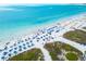 Aerial view of a vibrant, sun-soaked beach, highlighting clear blue waters and beachgoers enjoying the day at 5681 Midnight Pass Rd # 104, Sarasota, FL 34242