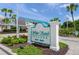 Welcoming sign for White Sands Village with well-kept landscaping and bright blue sky at 5681 Midnight Pass Rd # 104, Sarasota, FL 34242