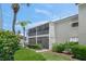 Exterior view of the building with a screened-in porch and tropical landscaping at 5681 Midnight Pass Rd # 104, Sarasota, FL 34242