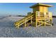 Sunny beach view featuring a classic yellow lifeguard stand, ensuring safety and a great time for beachgoers at 5681 Midnight Pass Rd # 104, Sarasota, FL 34242