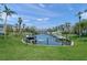 Scenic waterfront view with boat docks, lush green lawn, and tropical palm trees in a tranquil neighborhood at 5681 Midnight Pass Rd # 104, Sarasota, FL 34242