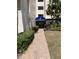 Inviting condo building entrance with a brick walkway, manicured landscaping, and a blue awning for convenient access at 6124 43Rd W St # 104A, Bradenton, FL 34210