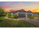 Charming villa exterior with a tile roof, brick driveway, landscaping, and a colorful sunset sky at 6250 Grandview Hill Ct, Bradenton, FL 34203