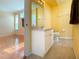 Bathroom with yellow walls, white cabinetry and hardware and beige flooring at 6307 Laurel Creek Trl, Ellenton, FL 34222