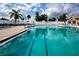 Large outdoor pool with marked lanes, blue lounge chairs, and palm trees, creating a resort-like atmosphere at 6307 Laurel Creek Trl, Ellenton, FL 34222