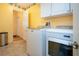 Laundry room with yellow walls, tile flooring, washer and dryer, and upper cabinets for storage at 6307 Laurel Creek Trl, Ellenton, FL 34222
