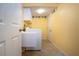 Bright laundry room with yellow walls, upper cabinets, utility sink, and a door to access other areas at 6307 Laurel Creek Trl, Ellenton, FL 34222