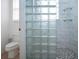 Modern shower featuring white tile, glass block window, and pebble stone floor at 6307 Laurel Creek Trl, Ellenton, FL 34222