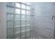 Modern shower featuring white tile, glass block window, and pebble stone floor at 6307 Laurel Creek Trl, Ellenton, FL 34222