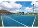 Outdoor tennis courts with blue surface, ideal for sports and recreation, next to a community building at 6307 Laurel Creek Trl, Ellenton, FL 34222