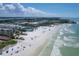 Breathtaking aerial view of beachfront condos, white sand, and ocean waves under a sunny blue sky with fluffy white clouds at 6480 Midnight Pass Rd # 311, Sarasota, FL 34242