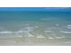 Coastal view of the beach, showing gentle waves and people wading in the clear ocean water at 6480 Midnight Pass Rd # 311, Sarasota, FL 34242