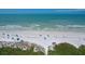 Beach view of the community beach with white sand, blue umbrellas, and distant ocean waves at 6480 Midnight Pass Rd # 311, Sarasota, FL 34242