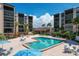 Community pool with umbrellas and chairs is nestled between buildings and lush landscaping at 6480 Midnight Pass Rd # 311, Sarasota, FL 34242