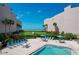 Community pool surrounded by lush landscaping, building exteriors, and a glimpse of the beach beyond at 6480 Midnight Pass Rd # 311, Sarasota, FL 34242