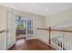 Upstairs hallway with hardwood floors and white railing overlooking the pool through the glass doors of the adjacent office at 6907 47Th E Ct, Ellenton, FL 34222