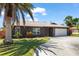Well-kept home with a two-car garage, a charming palm tree, and vibrant landscaping against a clear blue sky at 710 Beverly Rd, Venice, FL 34293