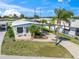 Inviting single-story home with lush lawn, complemented by mature palms and a cozy seating area on the porch at 714 N Waterway Dr, Venice, FL 34285