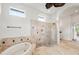This spacious primary bath features a soaking tub, glass enclosed shower, and travertine tile at 7832 Panther Ridge Trl, Bradenton, FL 34202