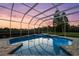 Backyard pool reflecting the colors of a vibrant dusk sky, surrounded by lush greenery and privacy at 7832 Panther Ridge Trl, Bradenton, FL 34202