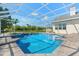 Backyard pool enclosed with screens, stone pavers, and manicured greenery under a blue sky at 7832 Panther Ridge Trl, Bradenton, FL 34202