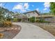 Side view of stone-accented home with a winding driveway and unique landscaping at 8255 Longbay Blvd, Sarasota, FL 34243