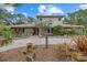 Charming stone-accented home featuring a unique, landscaped front yard and a red front door at 8255 Longbay Blvd, Sarasota, FL 34243
