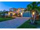 Inviting home featuring a paver driveway, lush landscaping, and a three-car garage at 8272 Redonda Loop, Bradenton, FL 34202