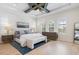 Bright main bedroom featuring wood floors, a ceiling fan, a blue rug and a large window with white shutters at 8272 Redonda Loop, Bradenton, FL 34202