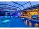 An outdoor pool at twilight features a wall-mounted TV, an outdoor kitchen, and lounge chairs at 8272 Redonda Loop, Bradenton, FL 34202