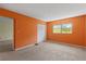 This bedroom features neutral carpet, an orange painted walls, and a window with green foliage outside at 860 Virginia St # 304, Dunedin, FL 34698