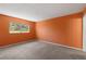 This bedroom features neutral carpet, an orange painted walls, and a window with green foliage outside at 860 Virginia St # 304, Dunedin, FL 34698