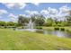Scenic pond with water fountain surrounded by lush greenery and blue sky at 8628 Milestone Dr, Sarasota, FL 34238