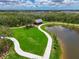 Aerial view of a park with a pond, a pavilion, a walking path, and green grass at 8916 Isabella Cir, Parrish, FL 34219