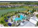 Aerial view of a community pool surrounded by palm trees and cabanas, near homes and a lake at 8916 Isabella Cir, Parrish, FL 34219