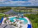 Aerial view of a community pool with a waterslide, palm trees, lounge chairs, and a lake in the background at 8916 Isabella Cir, Parrish, FL 34219