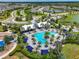 Aerial view of a community pool surrounded by palm trees and cabanas, near homes and a park at 8916 Isabella Cir, Parrish, FL 34219