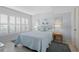Bedroom featuring blue walls and bedding, white plantation shutters, coastal decor and neutral tile flooring at 1001 Benjamin Franklin Dr # 106, Sarasota, FL 34236