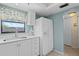 Bright kitchen features white cabinets, countertops, modern appliances, and a window with curtains at 1001 Benjamin Franklin Dr # 106, Sarasota, FL 34236