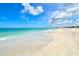 Wide sandy beach with clear turquoise water and a bright blue sky with fluffy white clouds at 105 Casey Key Rd # 20, Nokomis, FL 34275