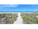 Sandy path through dunes leading to a pristine beach with clear, shallow water at 105 Casey Key Rd # 20, Nokomis, FL 34275
