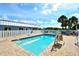 Refreshing community pool surrounded by a brick deck and white fence with community buildings nearby at 105 Casey Key Rd # 20, Nokomis, FL 34275