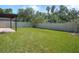 Backyard with green grass and a white privacy fence surrounded by mature trees at 110 San Lorenzo Ct, Bradenton, FL 34208