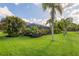 Expansive backyard featuring tropical landscaping, lush green grass, and a view of the home's screened-in pool area at 11410 57Th E St, Parrish, FL 34219