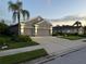 Exterior shot of a well-maintained house showcasing a three-car garage, manicured lawn, and professional lighting at 11410 57Th E St, Parrish, FL 34219