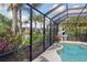 Screened-in pool area featuring an outdoor pizza oven, lush landscaping, and comfortable lounge area at 11410 57Th E St, Parrish, FL 34219